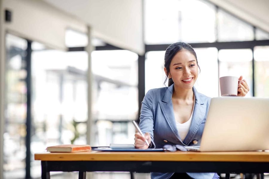 Asian Businesswoman Using laptop computer and working at office with calculator document on desk, doing planning analyzing the financial report, business plan investment, finance analysis concept.