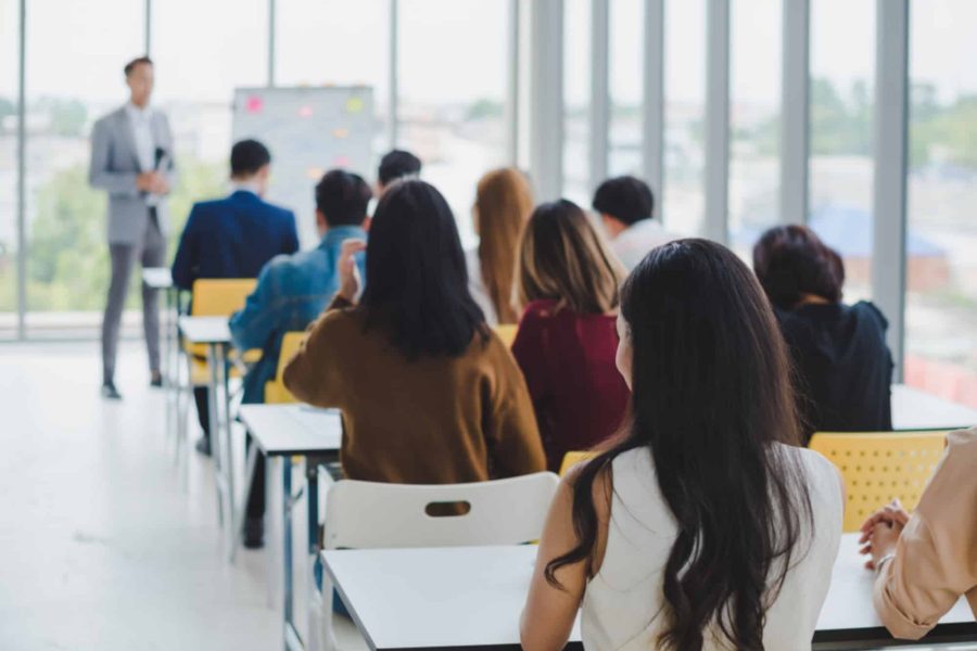Asian male speaker is speaking at seminars and workshops to the people in the meeting.